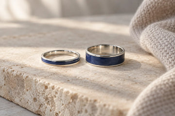 Editorial concept showing two blue enamel rings with contrasting face widths on pale stone