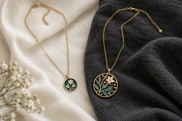 Concept comparison of small and large botanical enamel pendants on ivory and charcoal fabrics