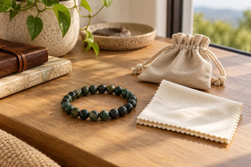 Natural stone bead bracelet beside a soft cloth and travel pouch on a sunlit desk